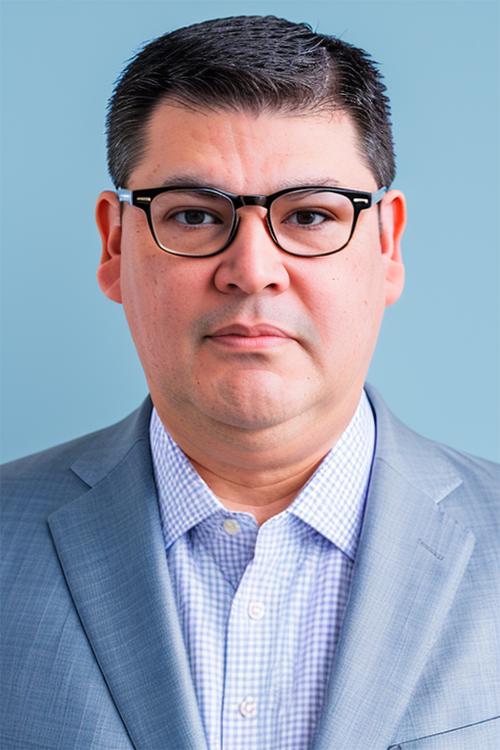 Portrait of Jason I. Hernandez, MSU's new chief human resources officer, with a blue background