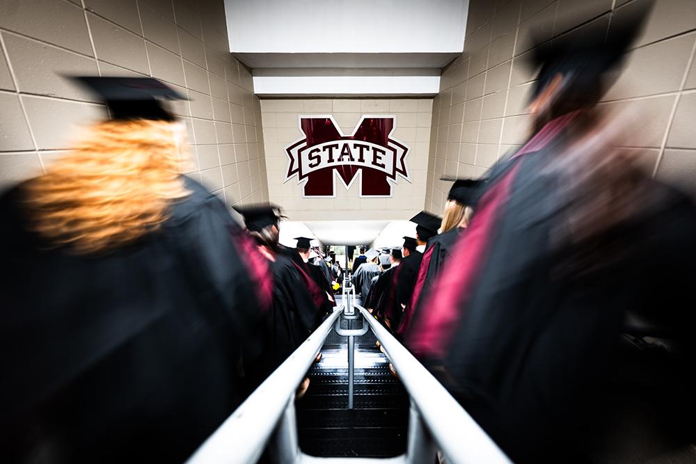 MSU graduates walk down the stairs to commencement ceremonies at Humphrey Coliseum.