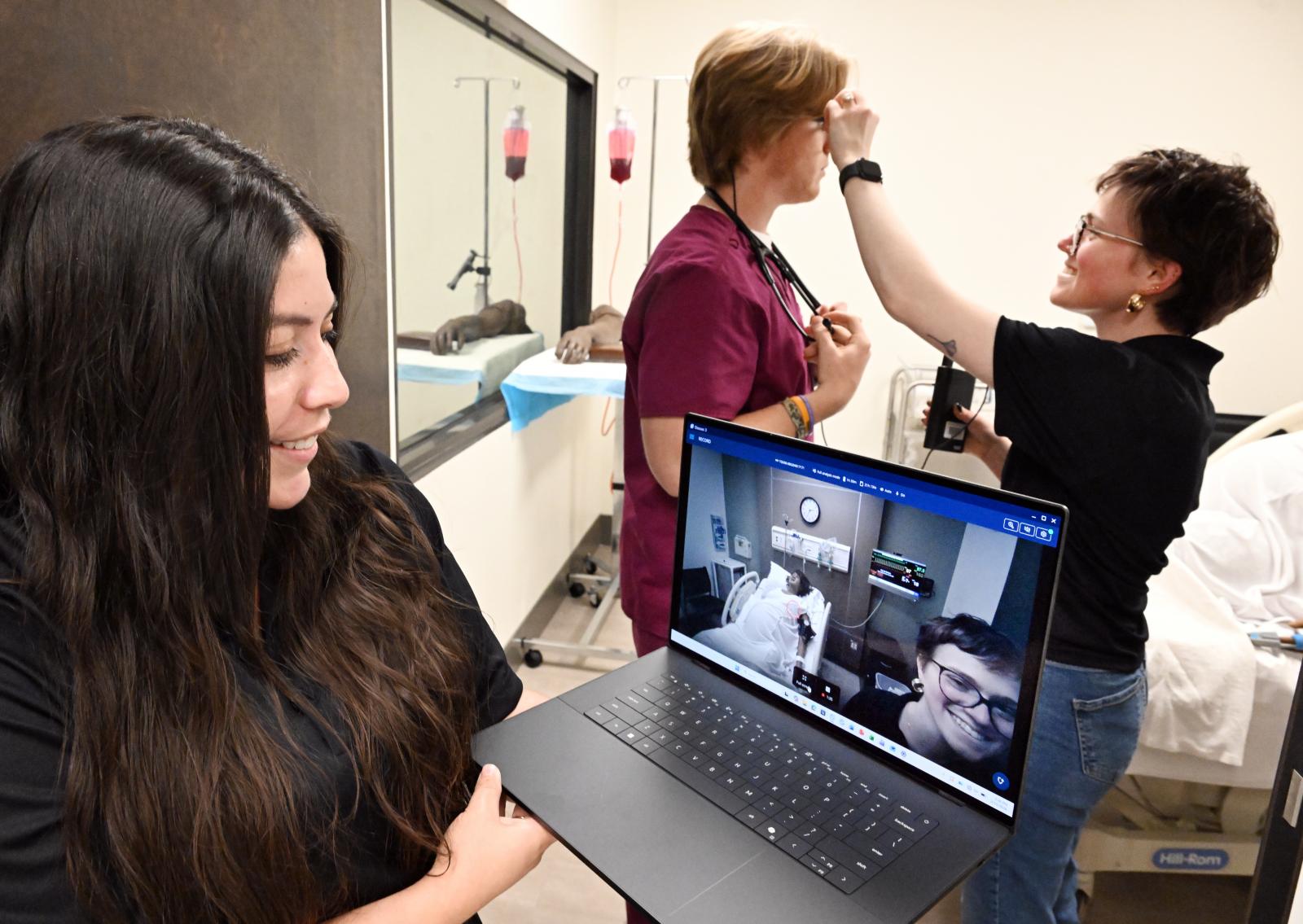 photo of an engineering student putting eye tracking glasses on a student while someone else does tracking on a computer