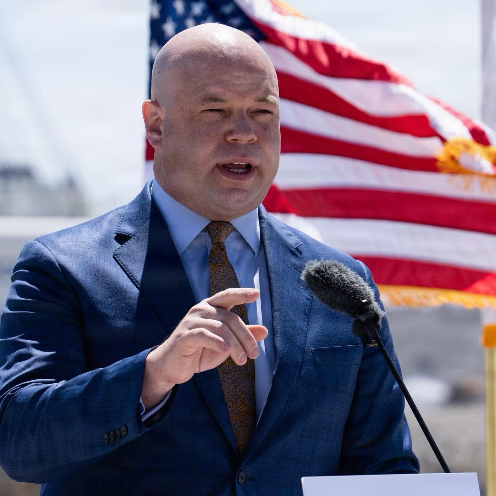Portrait of Adam Telle speaking at a podium
