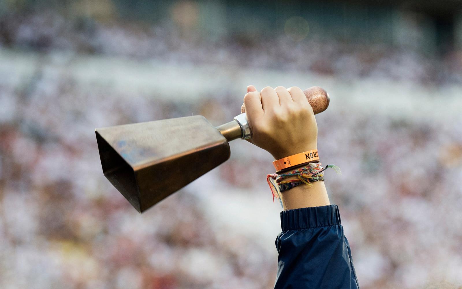 A close-up of a cowbell in someone's hand at a football game