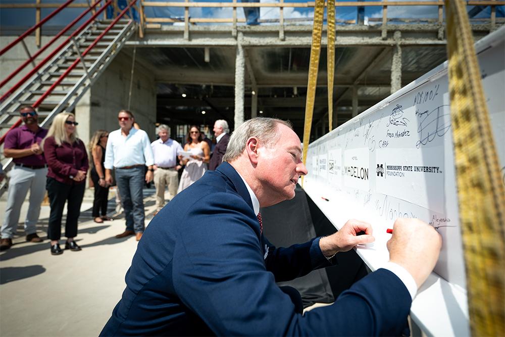 MSU President Mark E. Keenum signs a steel beam atop Hotel Madelon,