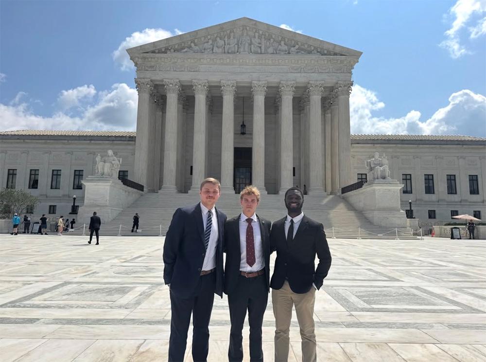 Three MSU students wearing suits and ties stand in front of the U.S. Supreme Court